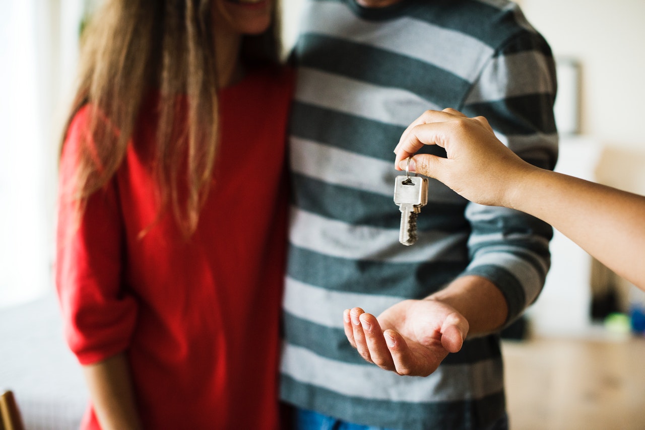 Hand of a man and woman holding a key together as a symbol of shared property investment