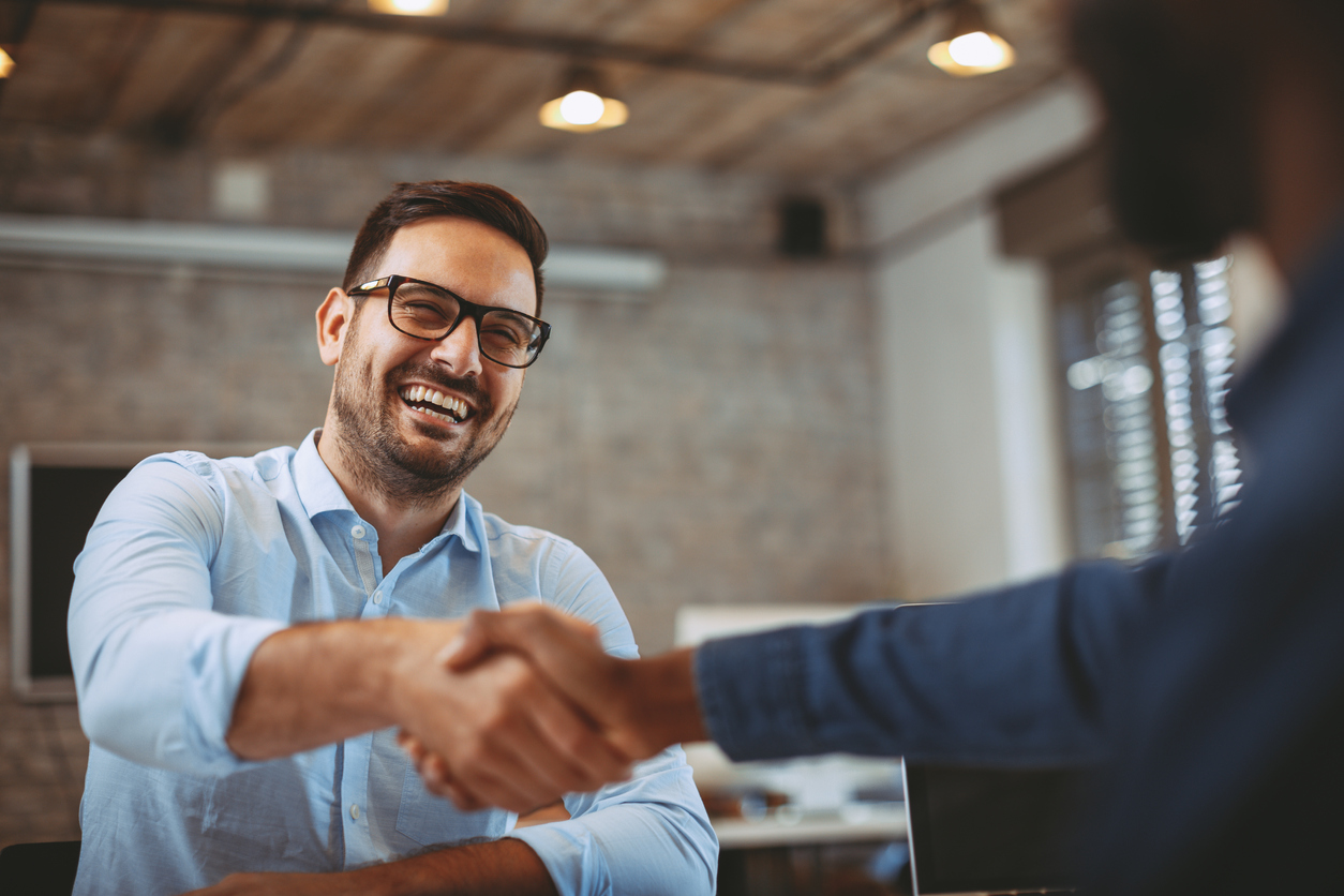 Smiling businessman shaking hands in modern office environment
