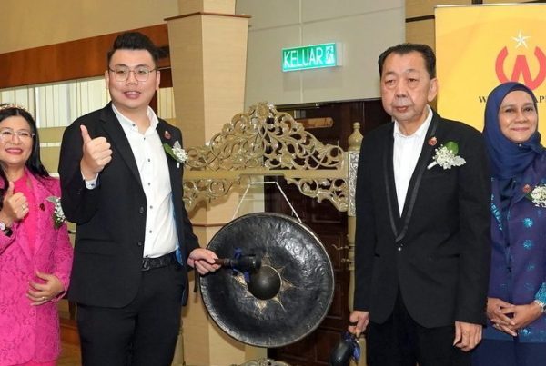 Portrait of Winstar beside a gong, preparing to strike it
